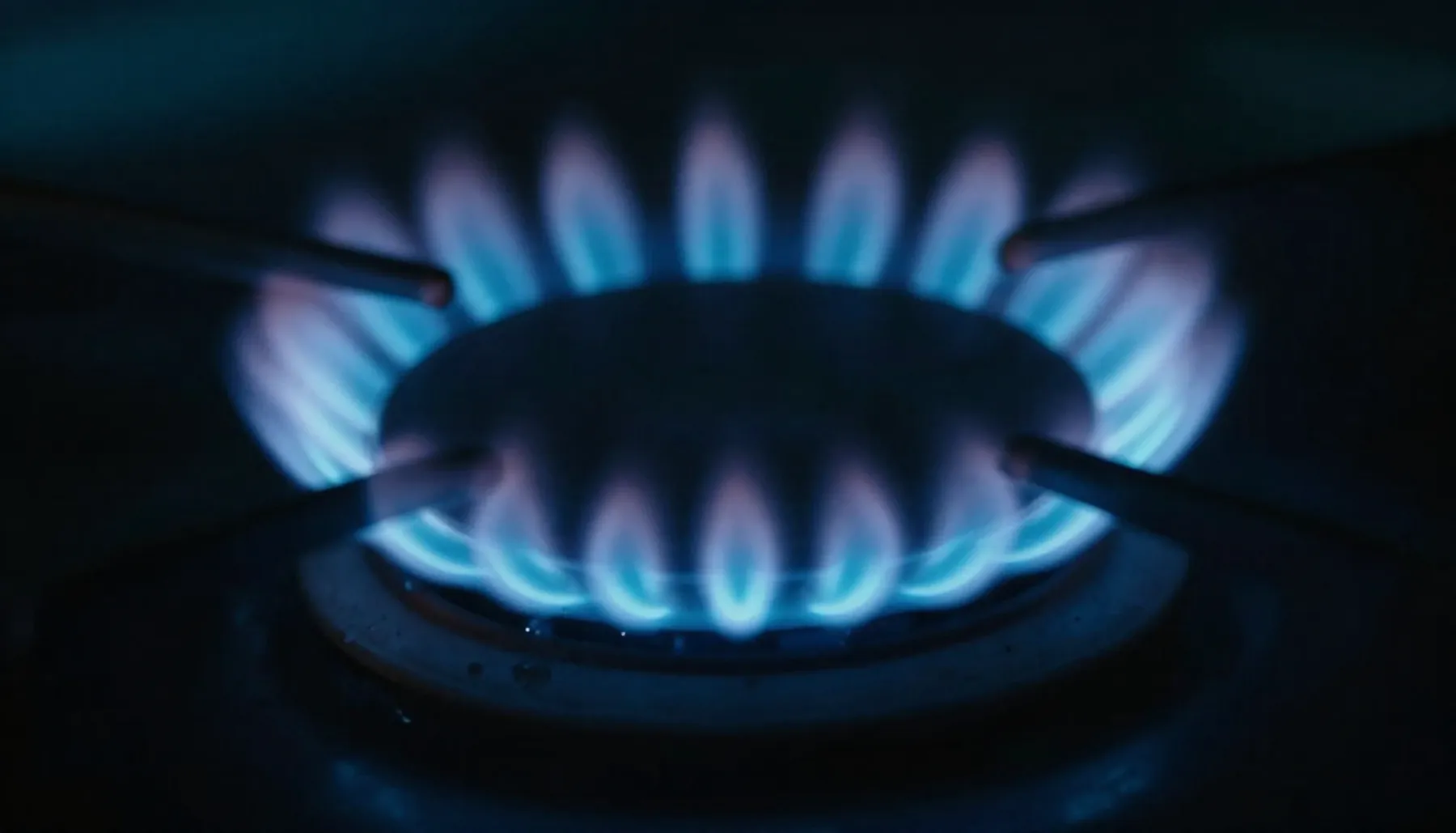 Ilustración: quemador de gas con flama azul limpia en la oscuridad.